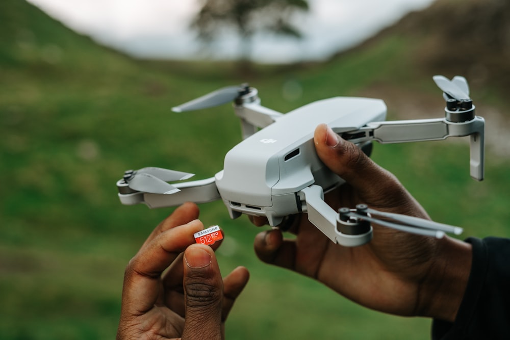 person holding white and gray drone