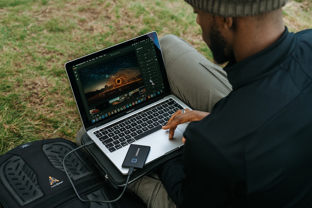 黒いジャケットを着た男がMacBook Proを使う