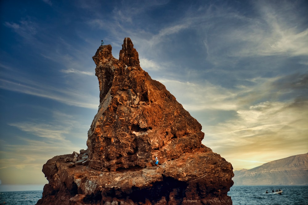 Formación rocosa marrón en el mar bajo el cielo azul durante el día