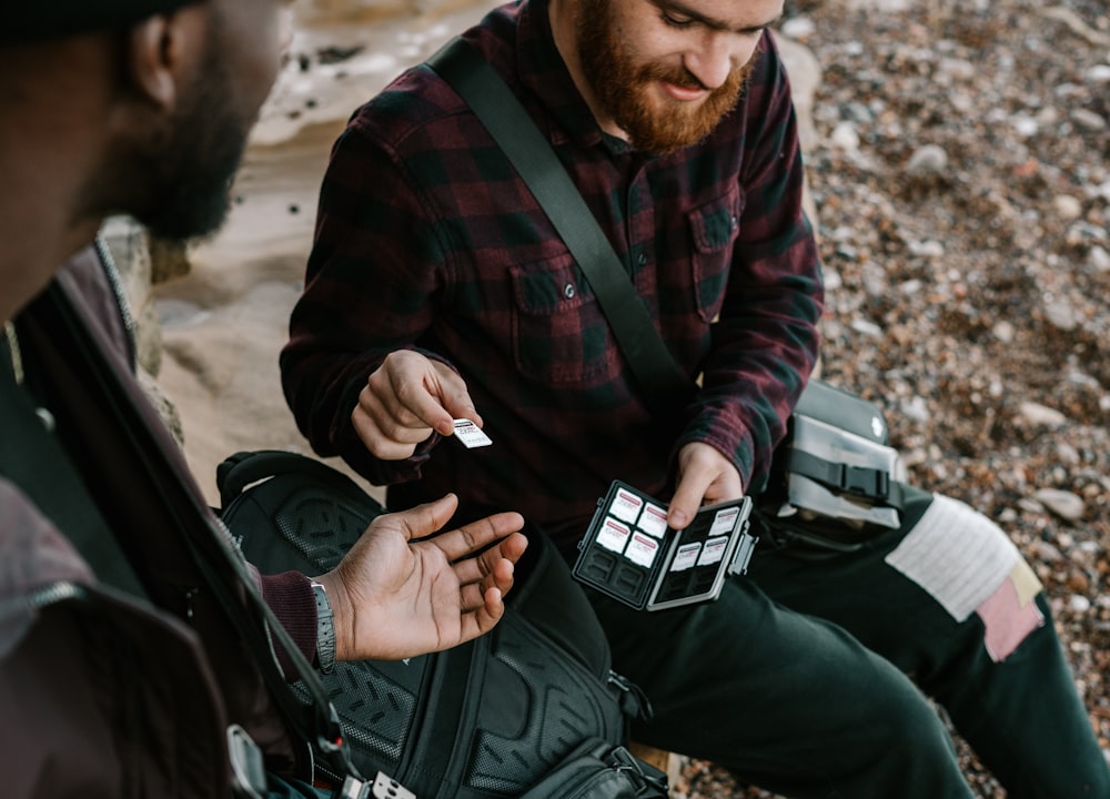 man in black and red plaid dress shirt holding white smartphone