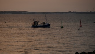 A fishing boat equipped with a GPS device sailing on calm waters at sunset.