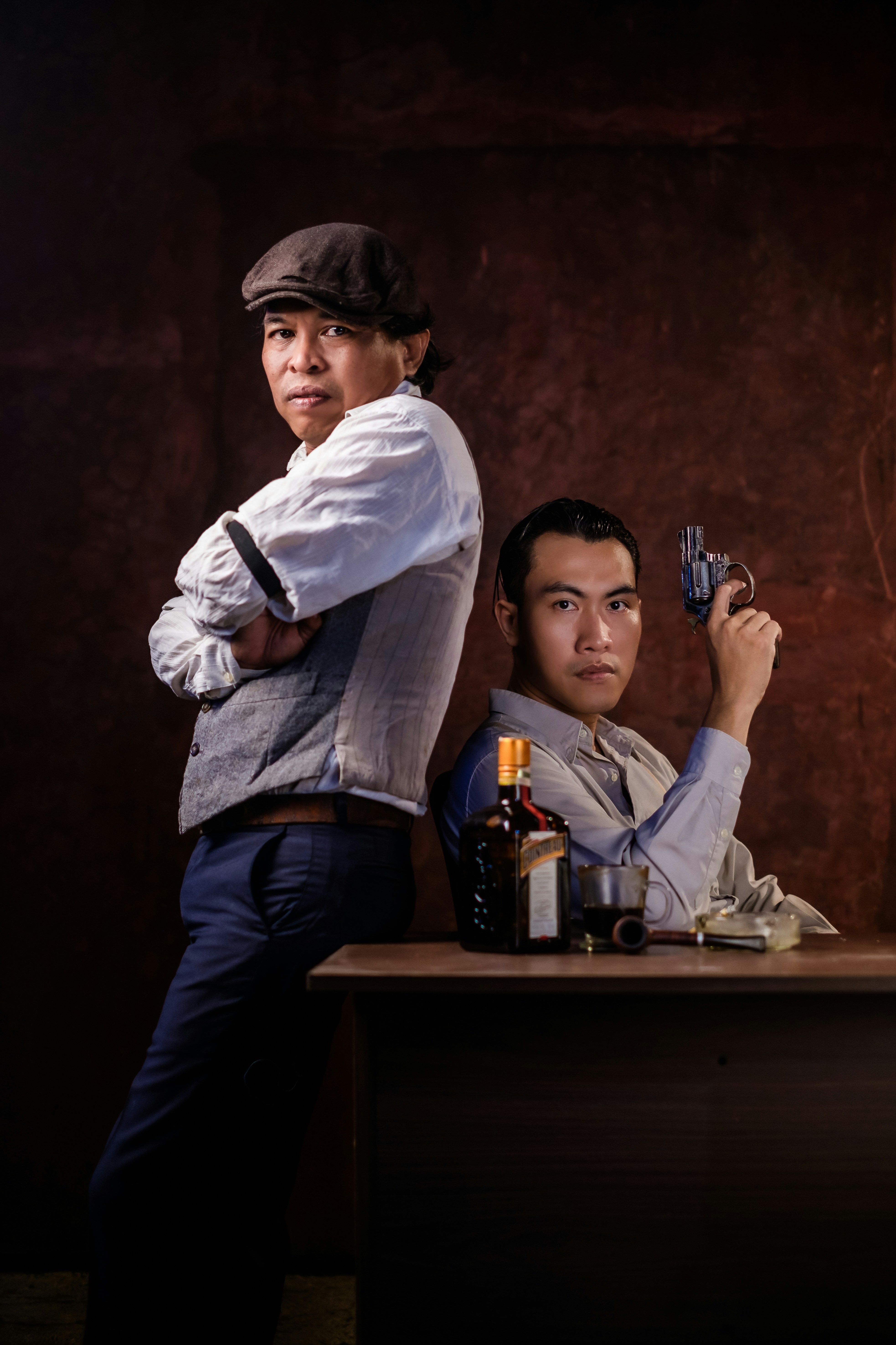 man in white dress shirt and blue denim jeans sitting on brown wooden table