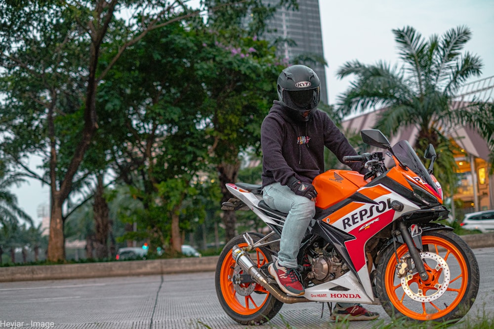 man in black and orange motorcycle helmet riding orange and black sports bike