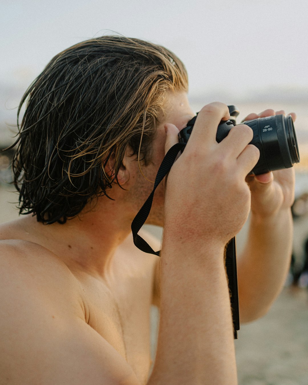 topless man holding black dslr camera