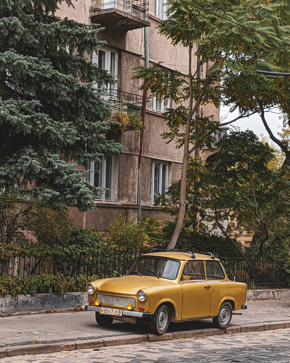 yellow car parked beside brown concrete building during daytime