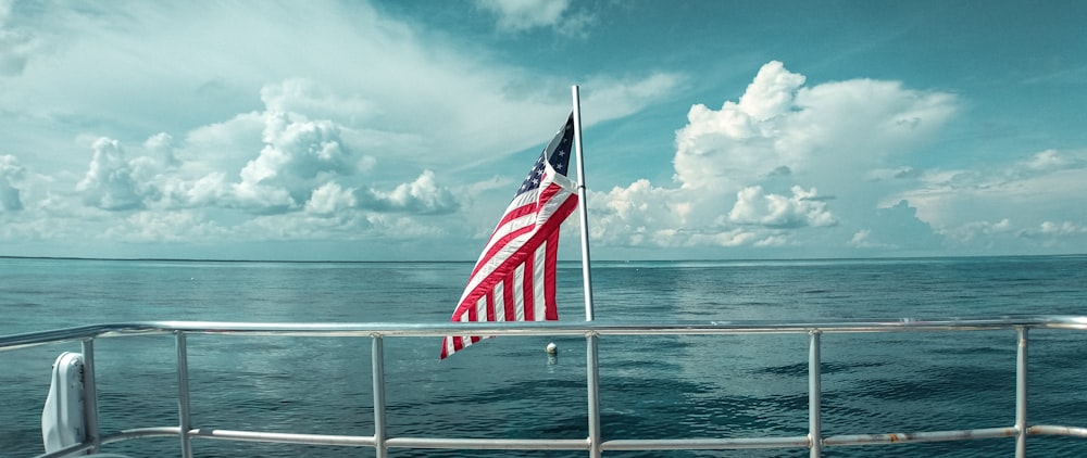 red white and blue flag on white metal pole near sea during daytime