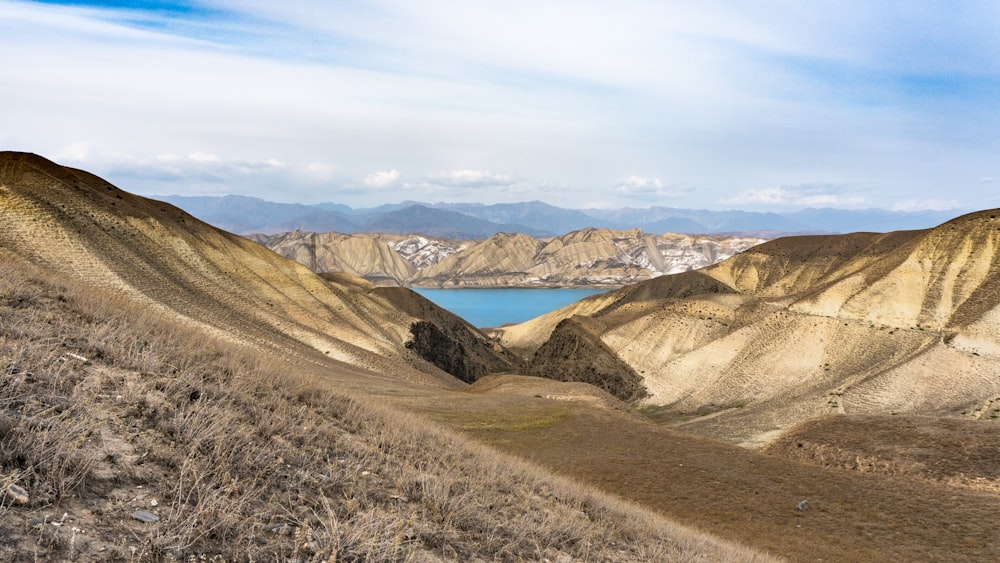 a view of a lake and mountains from the top of a hill