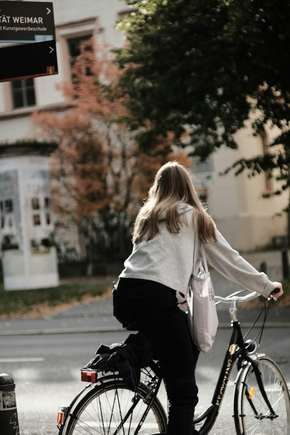 woman in white long sleeve shirt and black pants riding on black bicycle during daytime