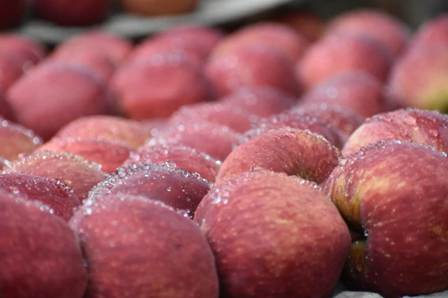 Bright red apples with dewdrops, arranged on rustic burlap fabric.