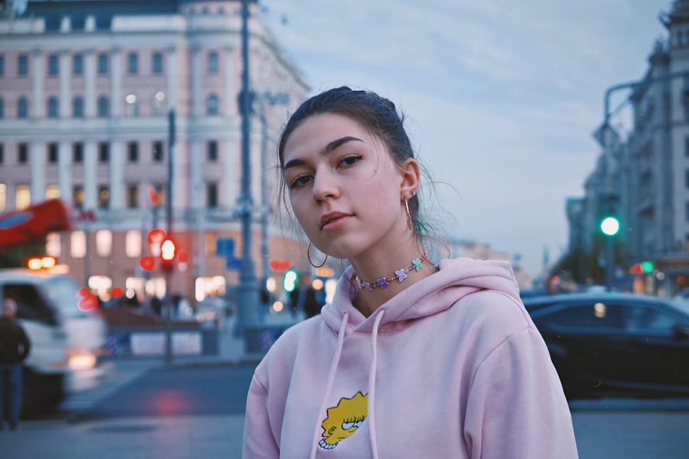 woman in pink hoodie standing near building during daytime
