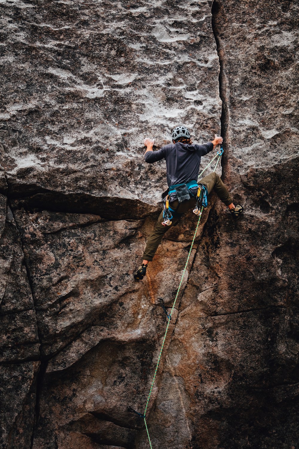 man in blue t-shirt climbing on brown rock during daytime