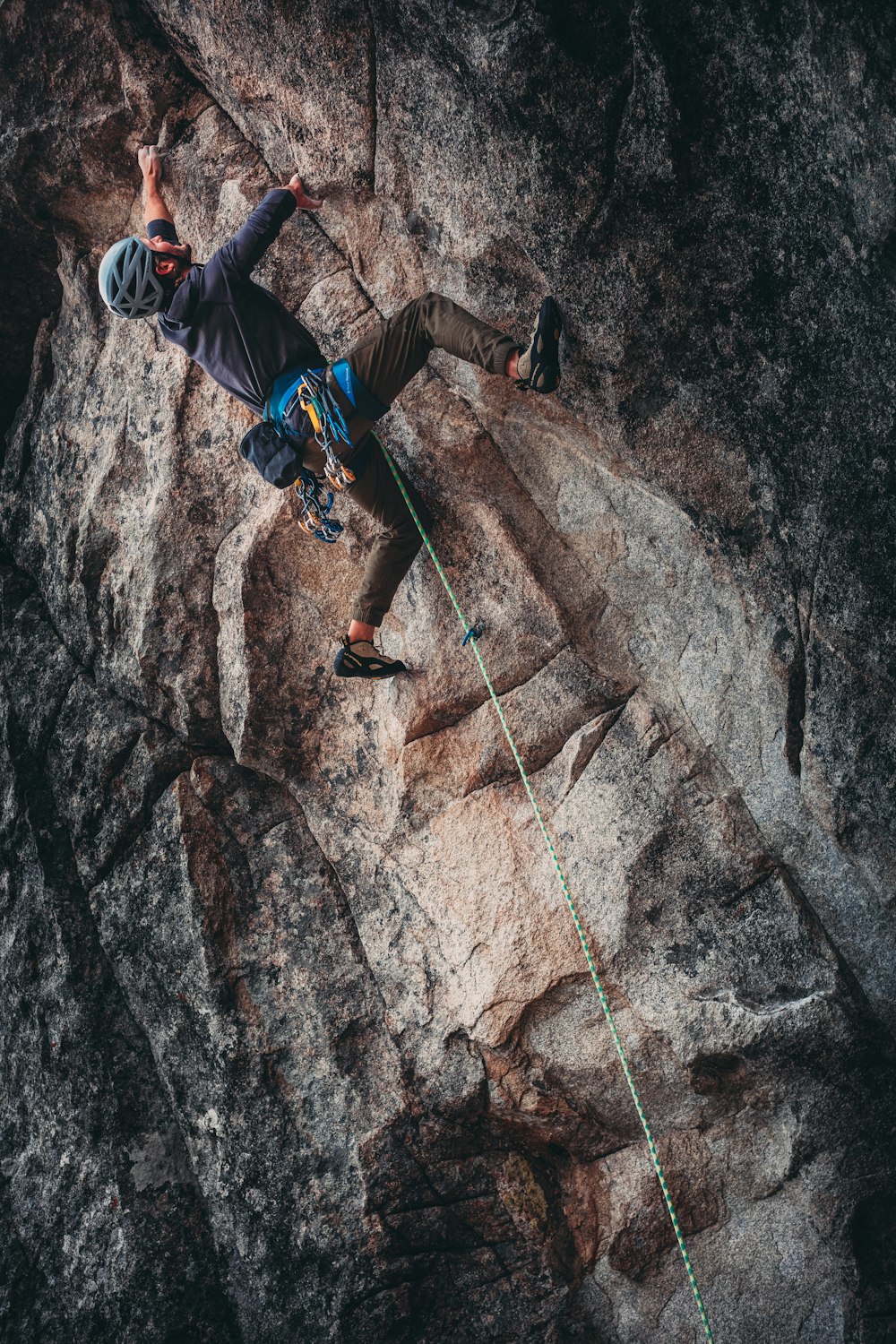 man in blue jacket climbing on brown rocky mountain during daytime