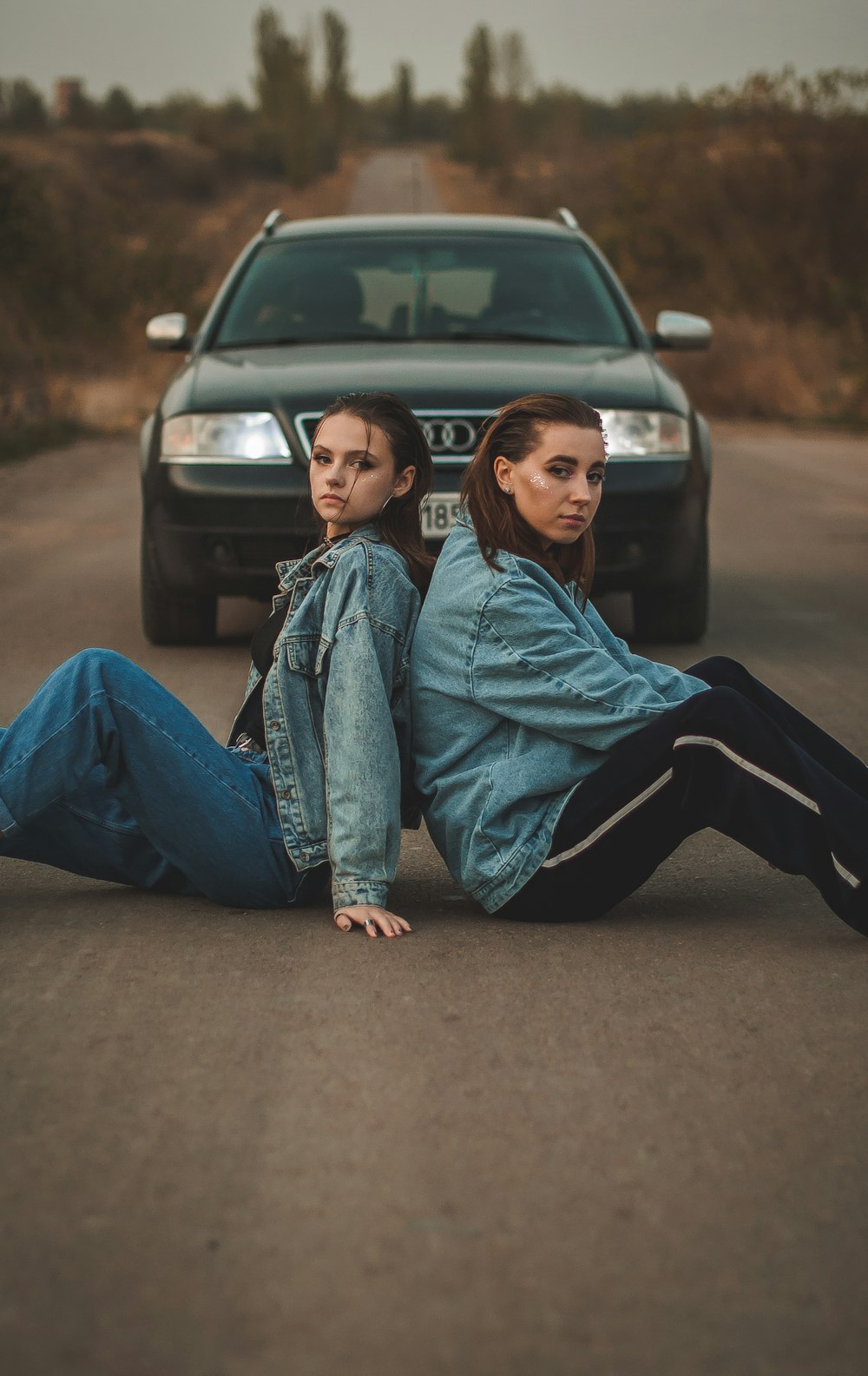 woman in blue denim jacket and black pants sitting on road