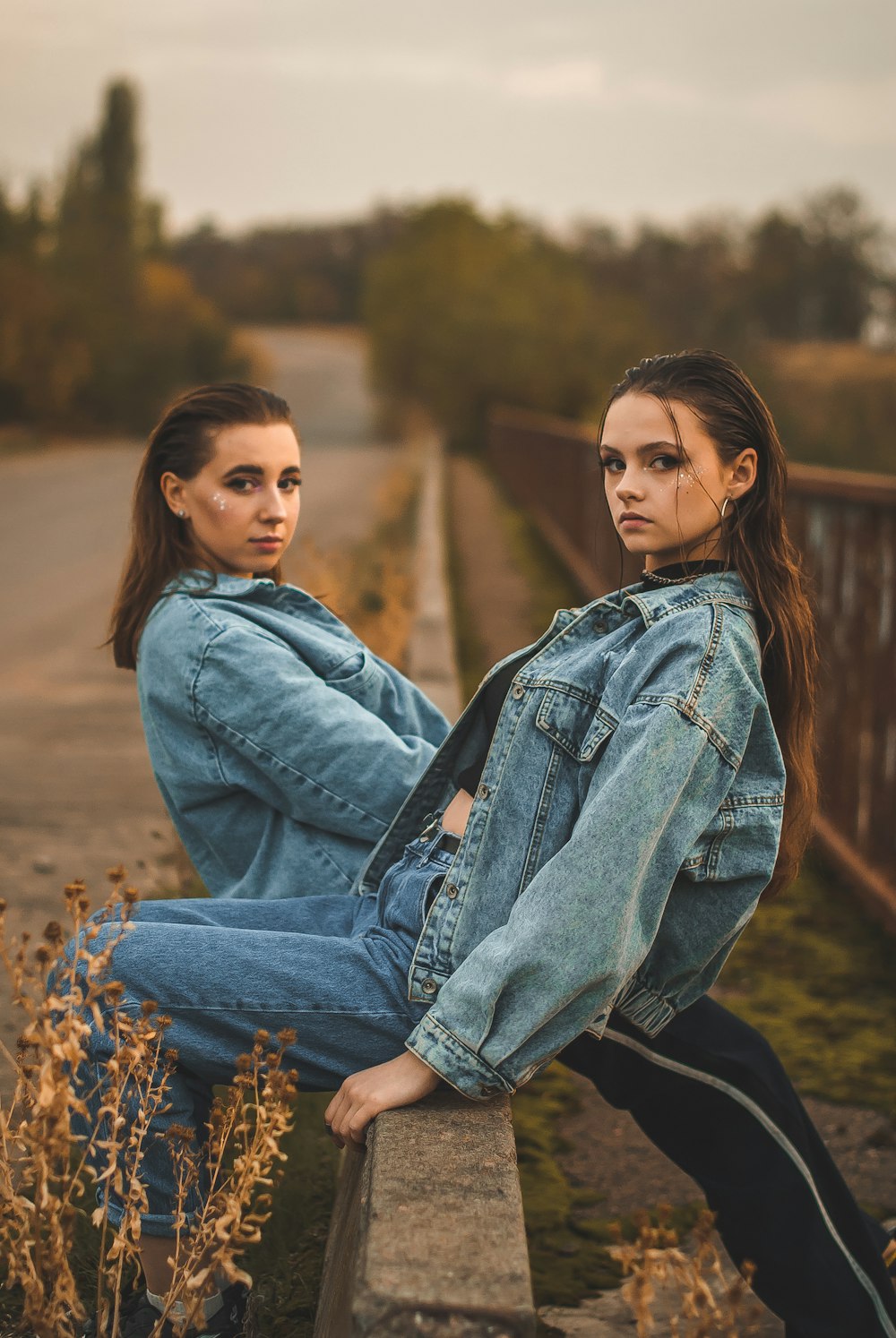 woman in blue denim jacket sitting on brown dried leaves during daytime