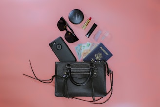 black leather sling bag beside black sunglasses and black sunglasses