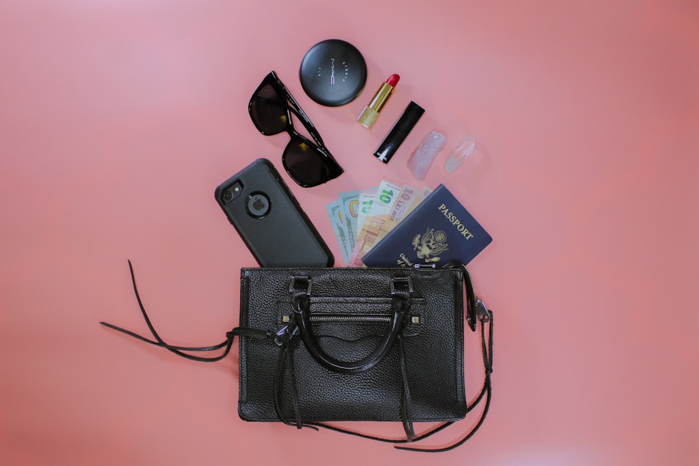 black leather sling bag beside black sunglasses and black sunglasses