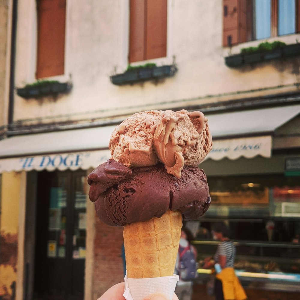 personne tenant un cornet de crème glacée brune