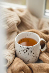 A calming flat lay of a journal, pen, and a cup of tea beside a soft blanket.