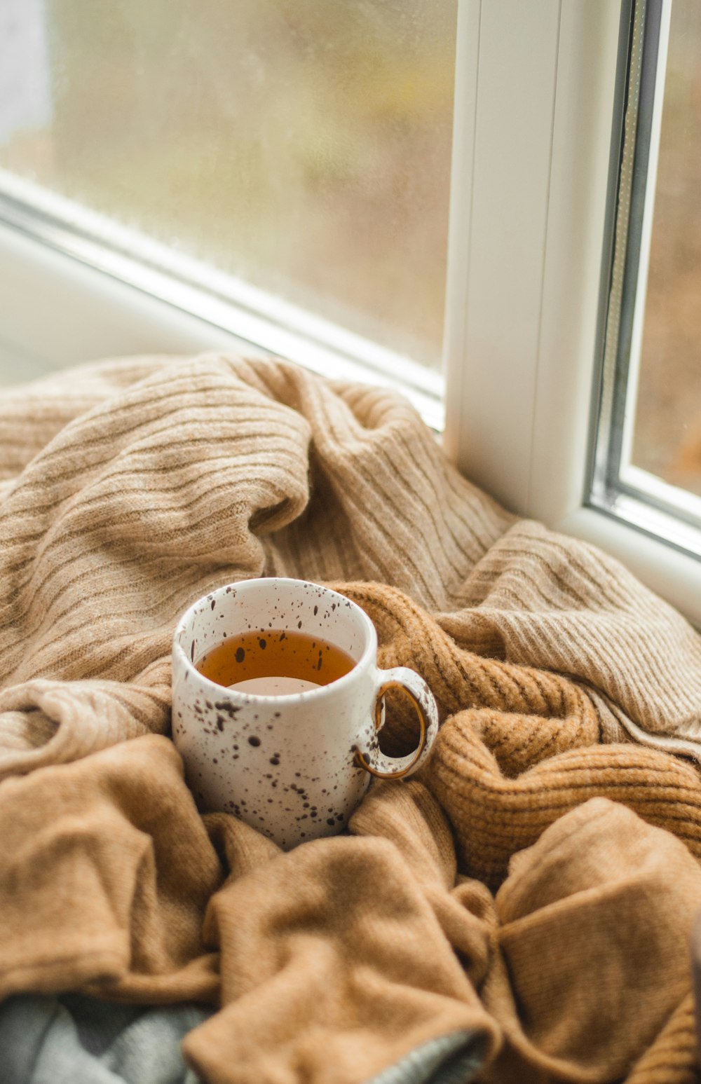 white ceramic mug on brown textile