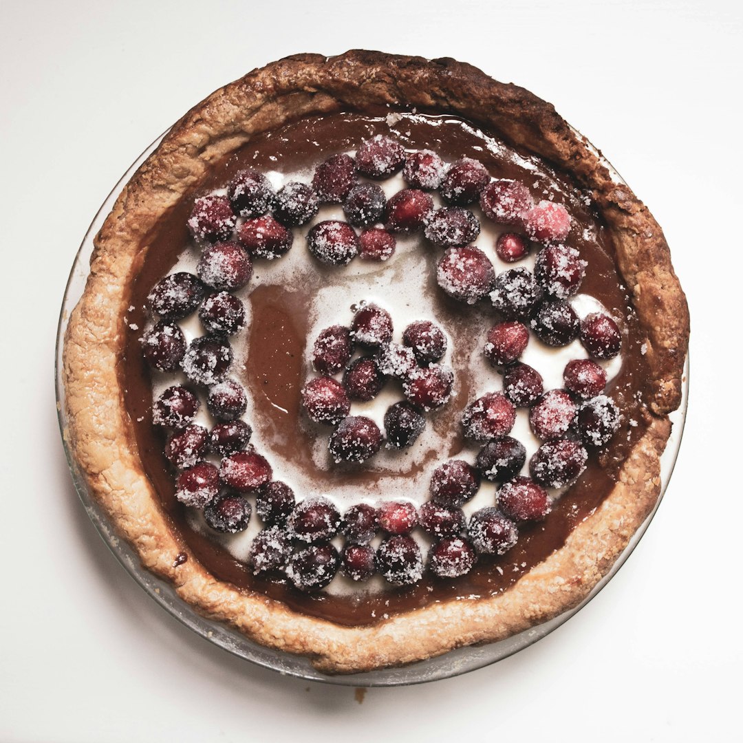 brown and black pie with red and black berries on top