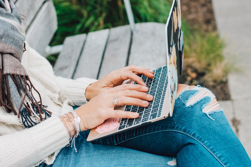 person in white long sleeve shirt and blue denim jeans using macbook pro