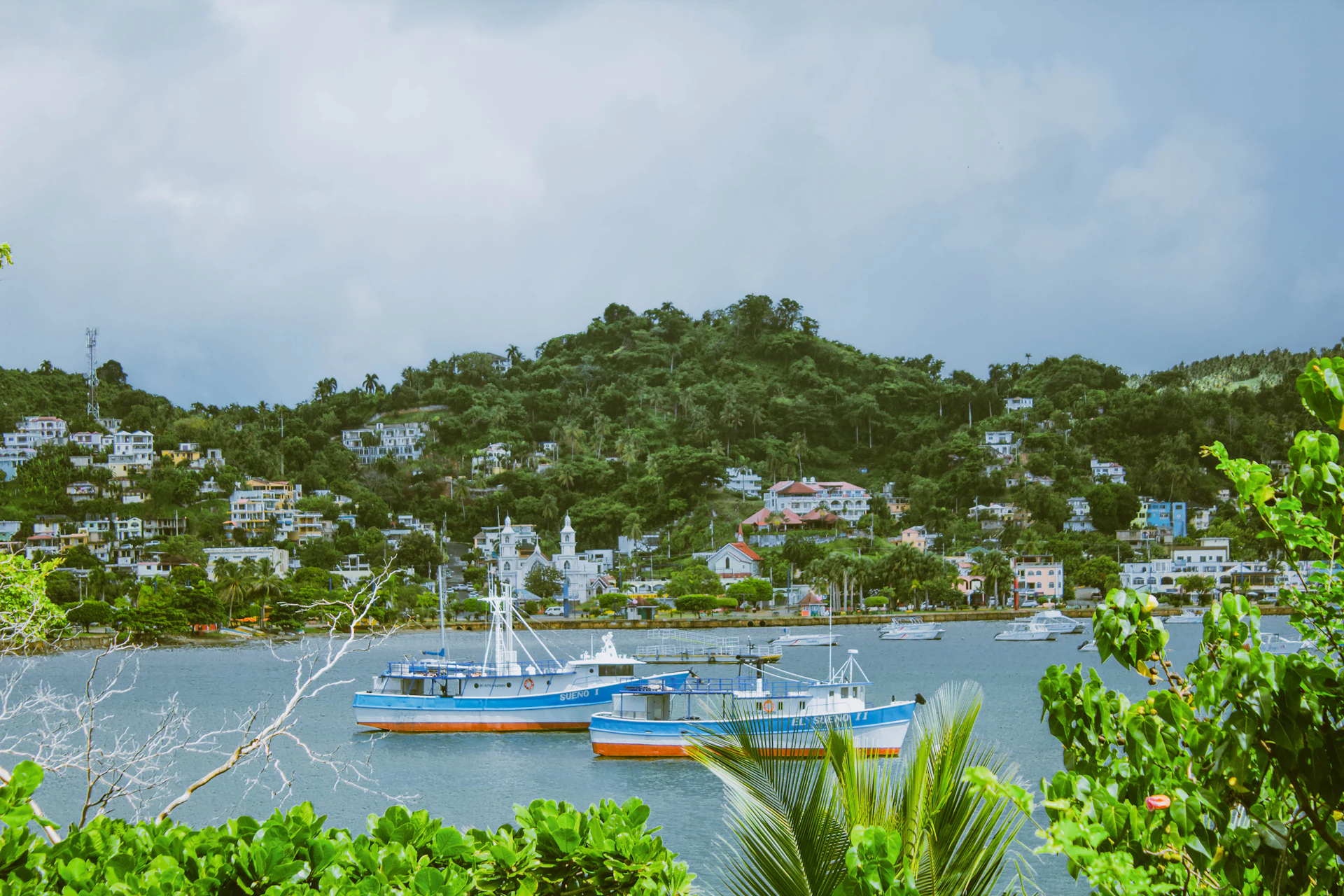 Boat on the water below green hills in Samaná