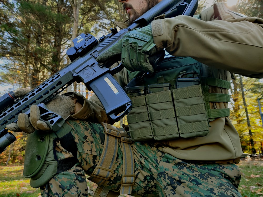 Homme en uniforme de camouflage vert et marron tenant un fusil noir