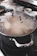 Close-up of a shiny stainless steel pot simmering a hearty stew on a stove.