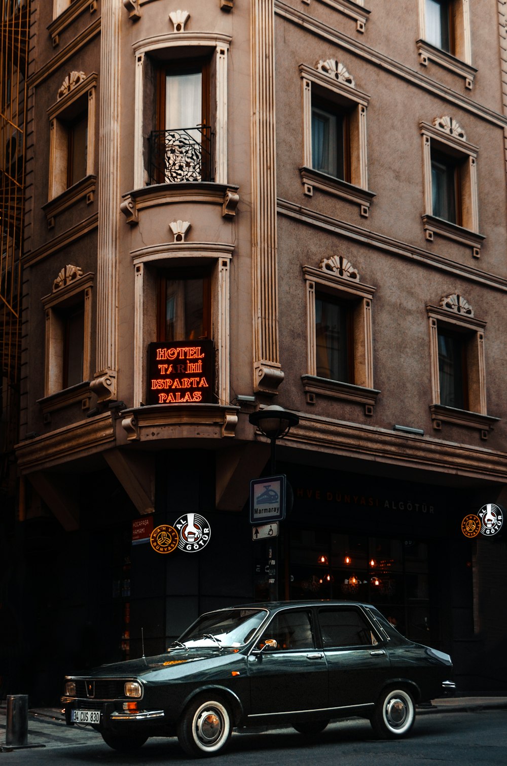 black car parked beside brown concrete building during night time