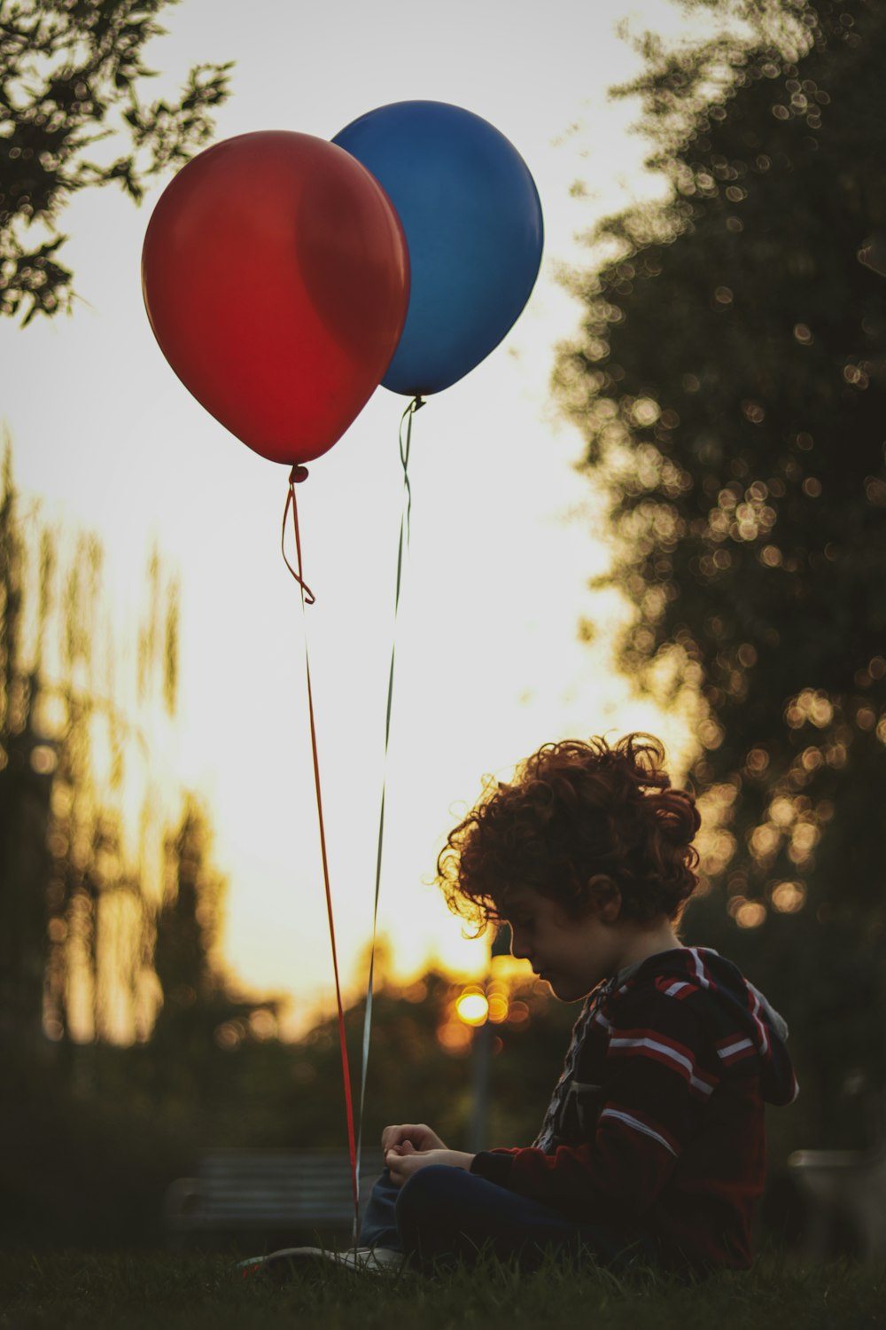 girl in blue and white stripe shirt holding balloons during daytime