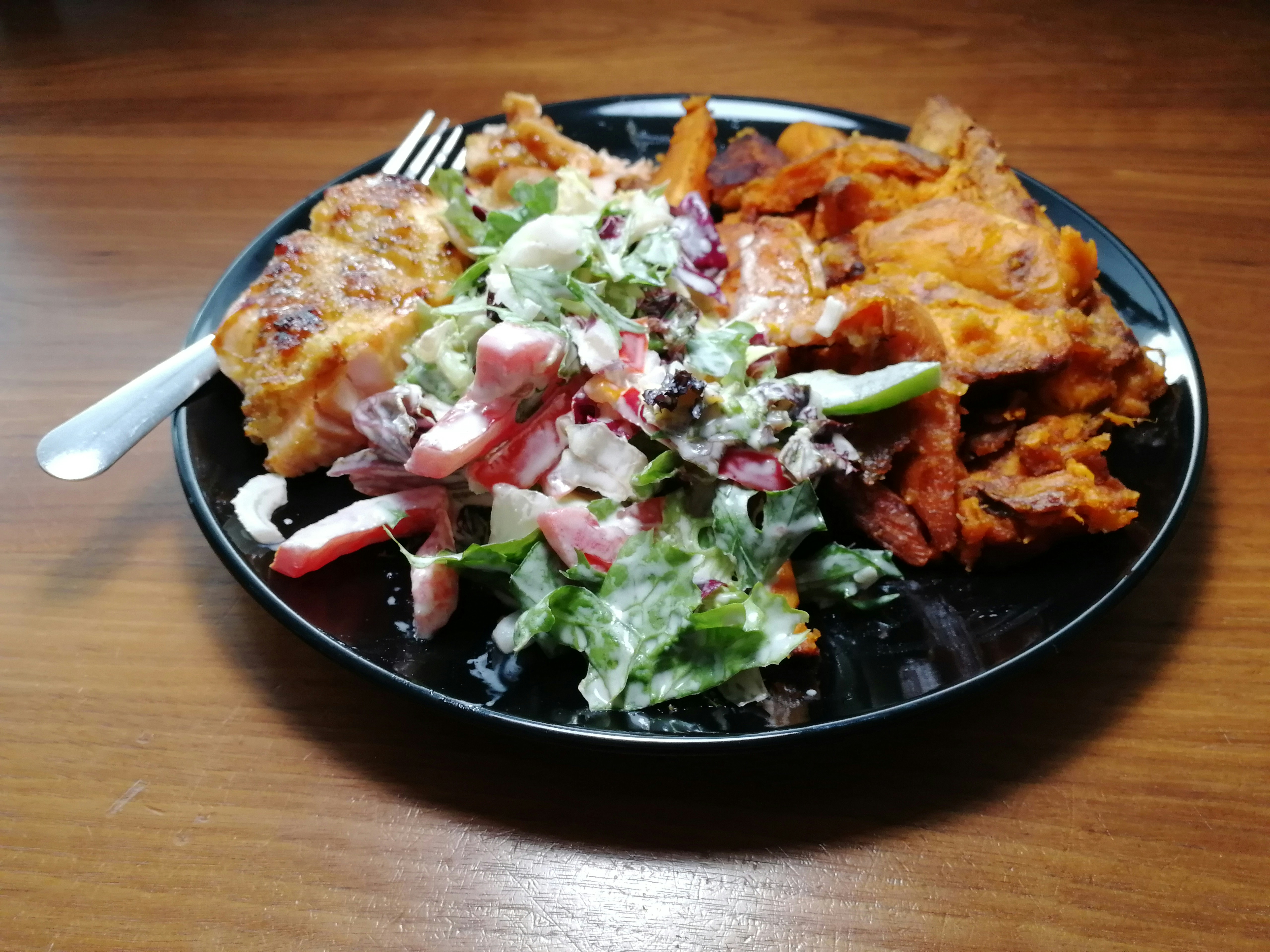 Enchiladas topped with crema, onion and greens on a black plate