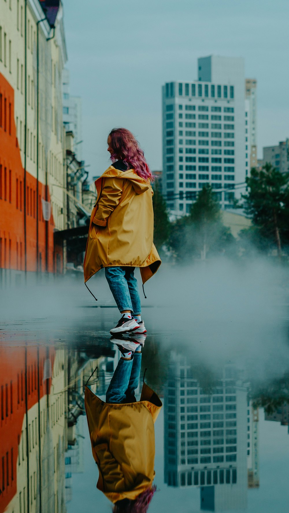 woman in yellow coat and blue denim jeans standing on black skateboard during daytime