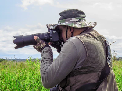 man in brown jacket holding black dslr camera