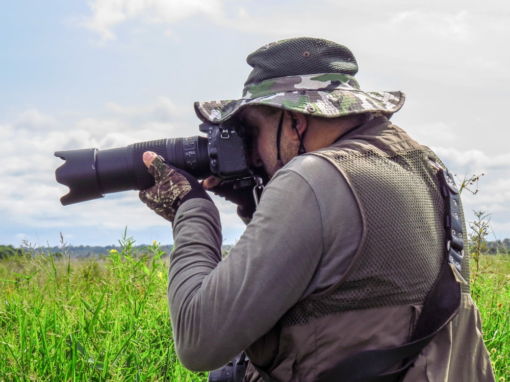 homem na jaqueta marrom segurando a câmera dslr preta