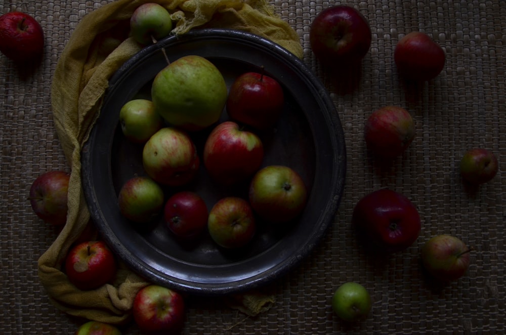 green and red apples in black round bowl