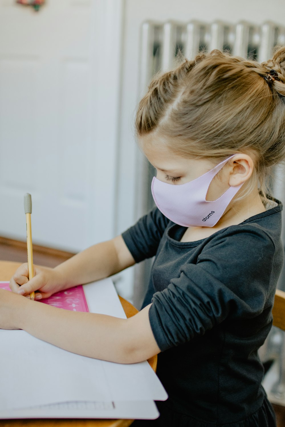 boy in black long sleeve shirt writing on pink paper