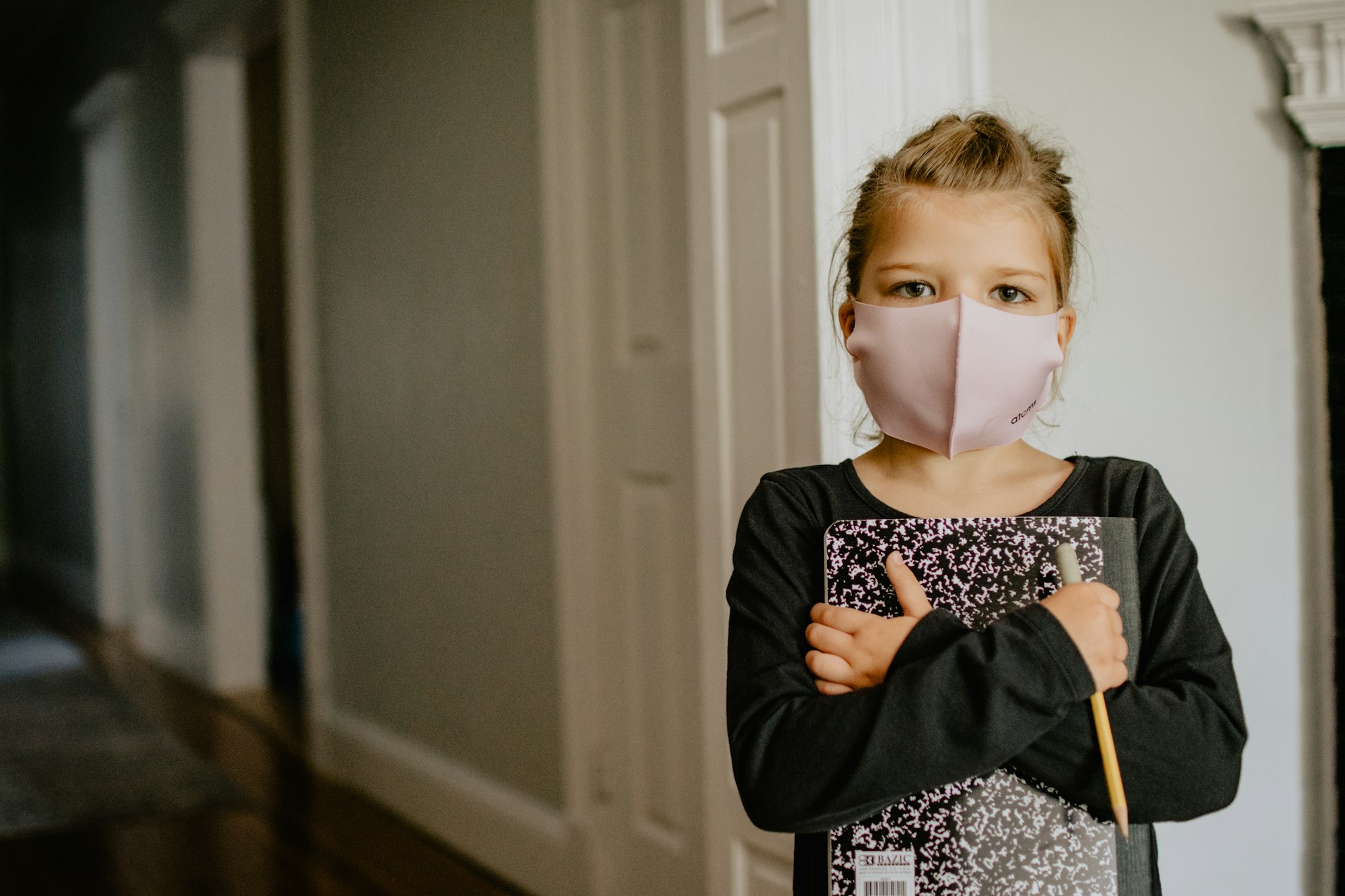 girl with school supplies and a mask on