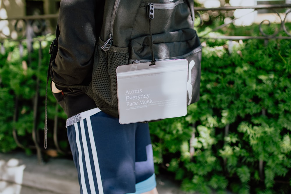 person in black jacket carrying white and black backpack