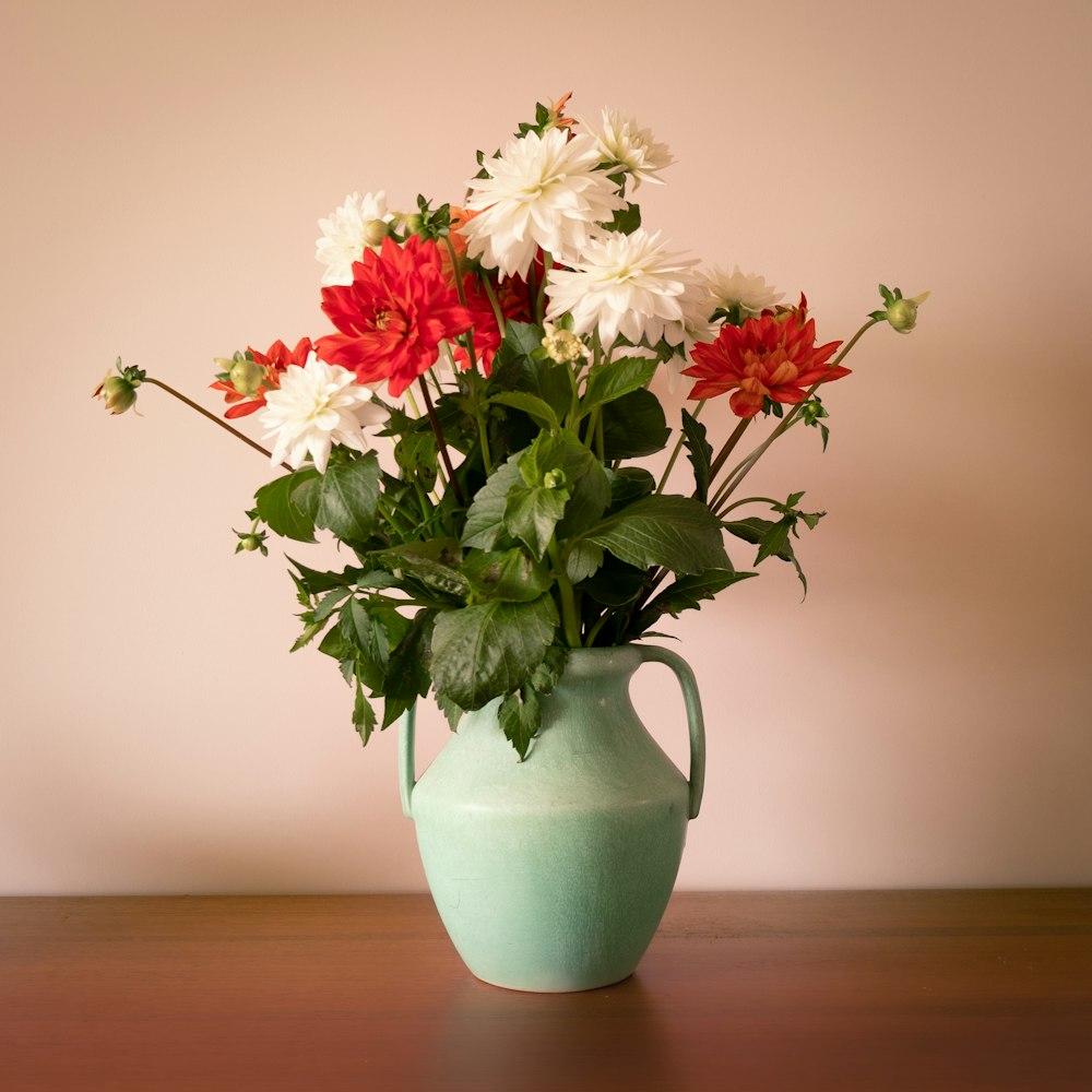white and red flowers in blue ceramic vase