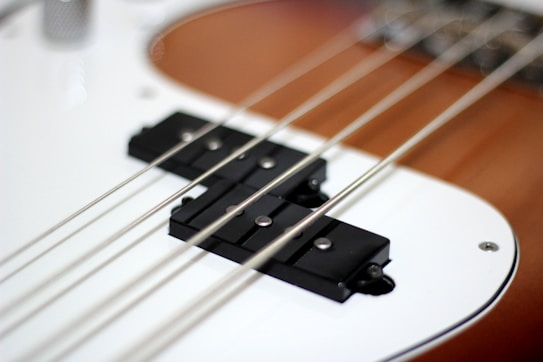Close-up of an electric guitar, focusing on the strings and pickups on the guitar body. The surface is glossy and features a sleek modern design.