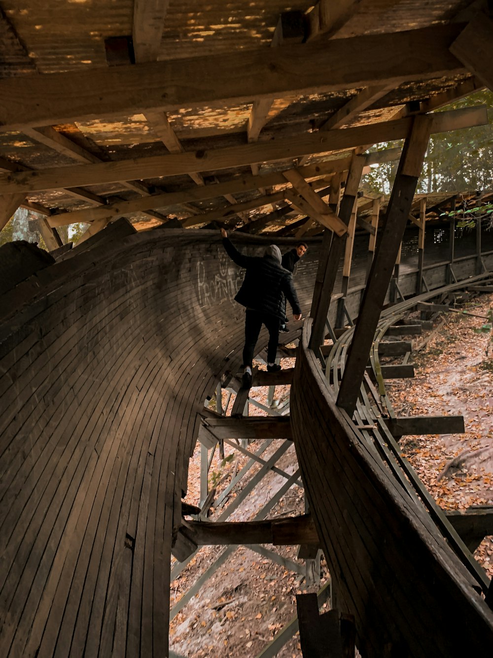 man in black jacket and pants standing on wooden bridge