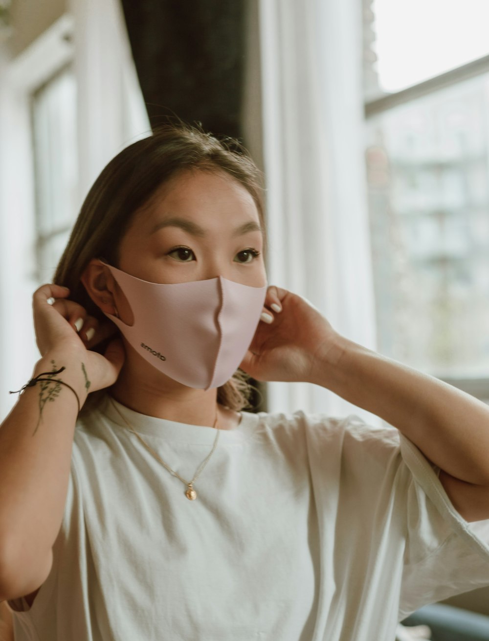 woman in white shirt covering her face with white mask