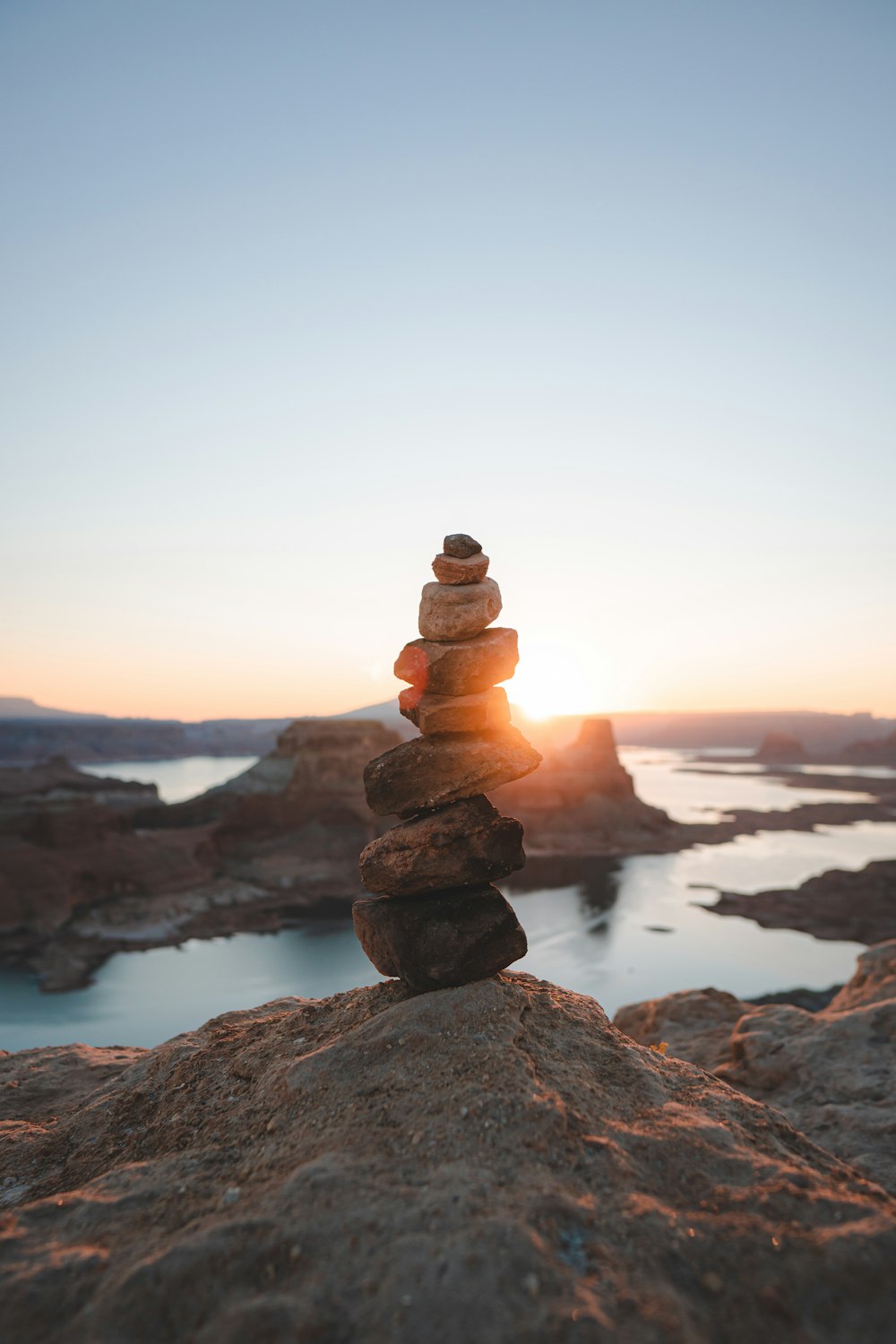 Steinstapel auf Felsen in der Nähe von Gewässern während des Sonnenuntergangs