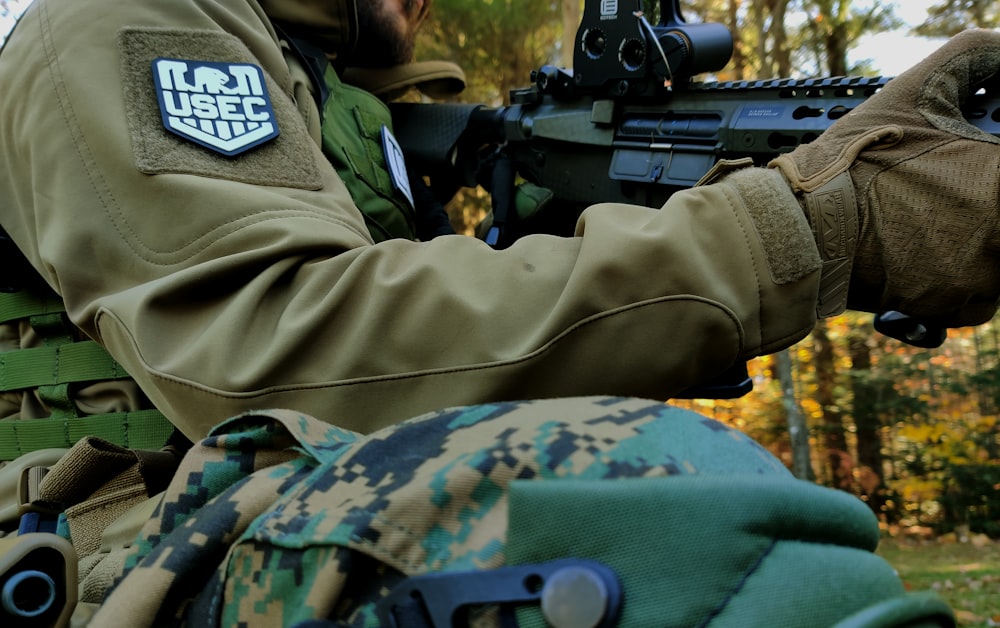 Uomo in uniforme mimetica verde e marrone dell'esercito che tiene il fucile