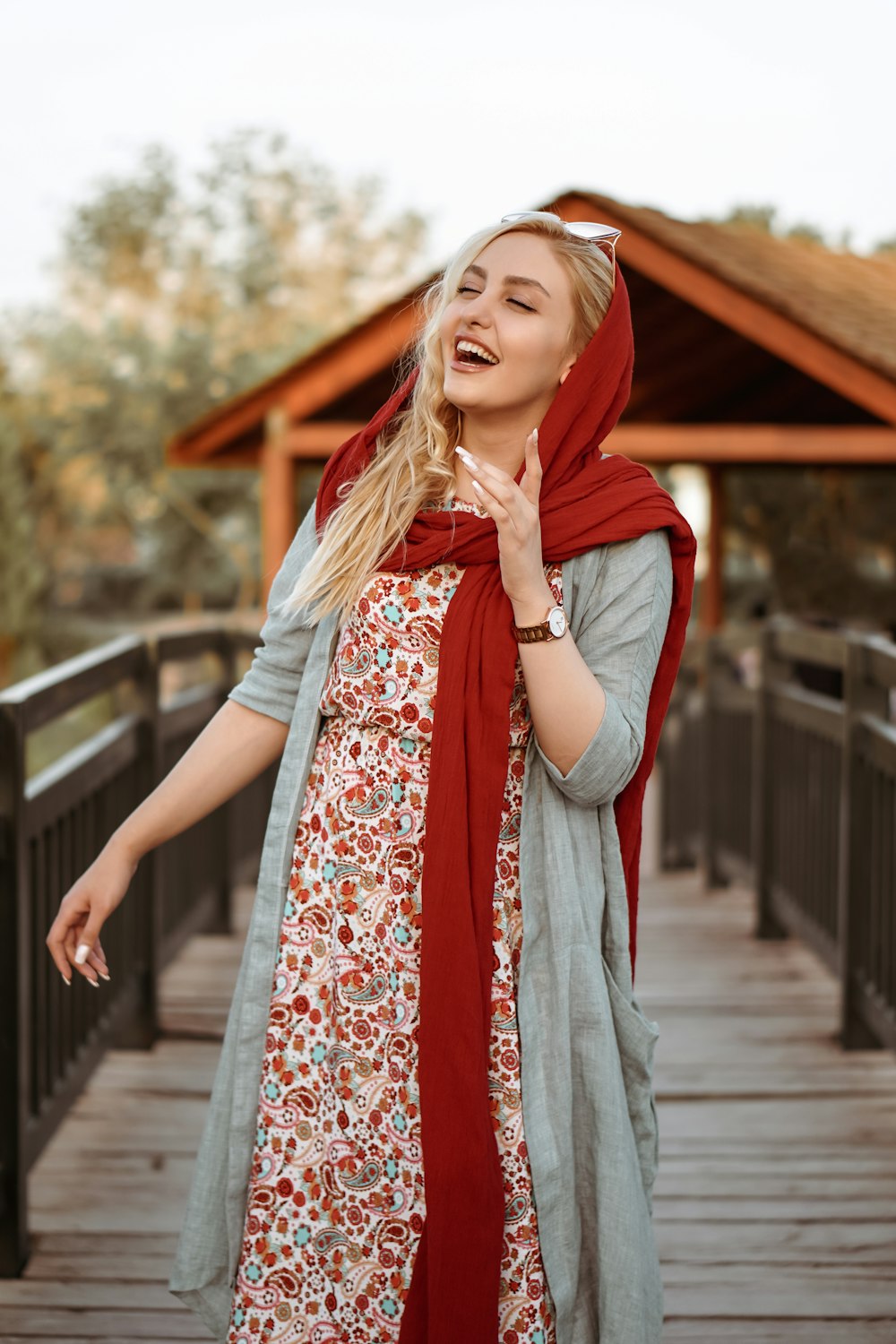 Femme en hijab rouge debout sur un pont en bois