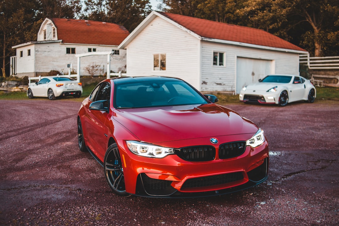 red bmw car parked near white house during daytime