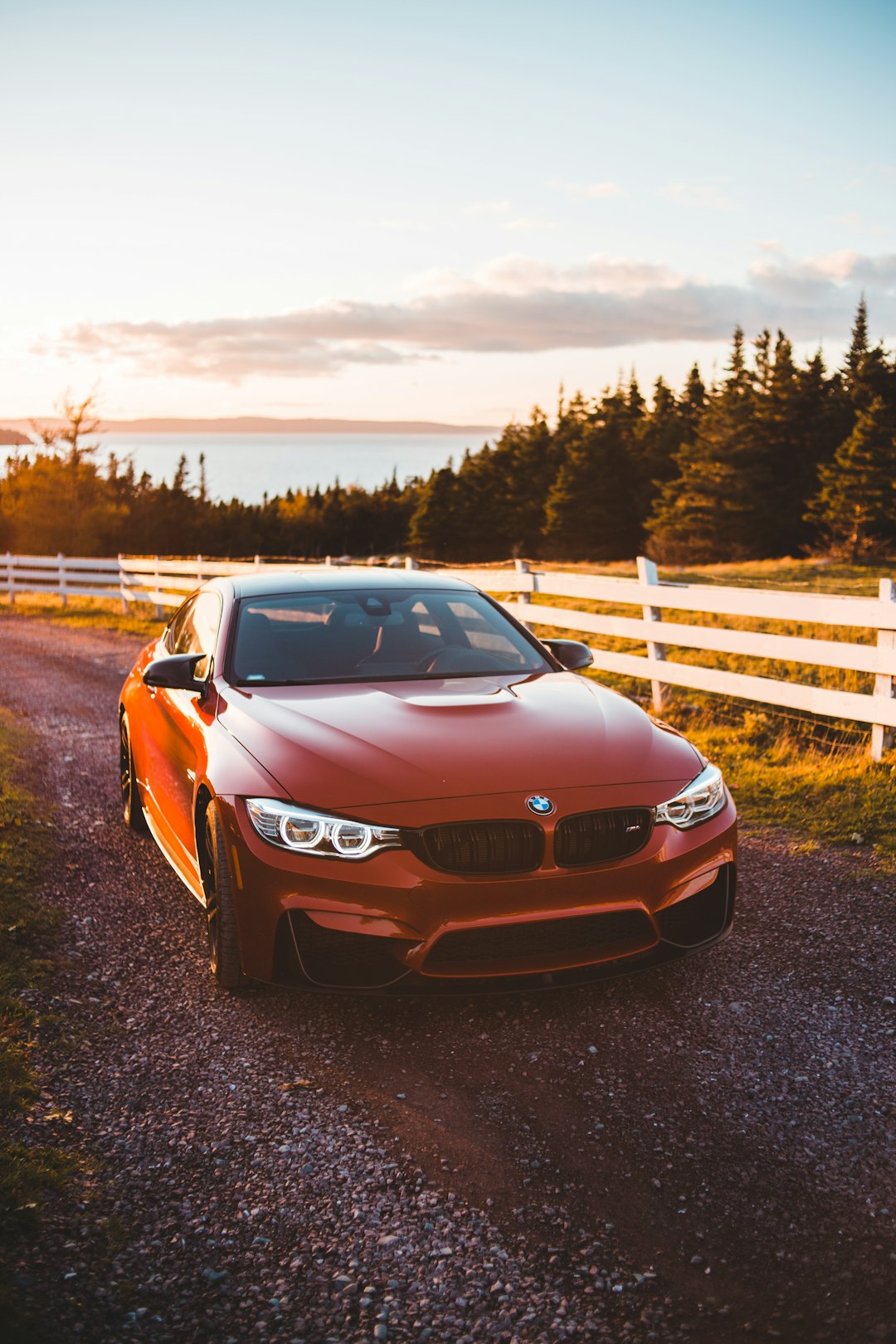 brown bmw m 3 parked on dirt road near wooden fence during daytime