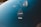 A black tree-shaped air freshener labeled 'Little Trees' and 'Black Ice' hangs inside a vehicle. It is attached to the rearview mirror and is set against a softly focused blue backdrop.