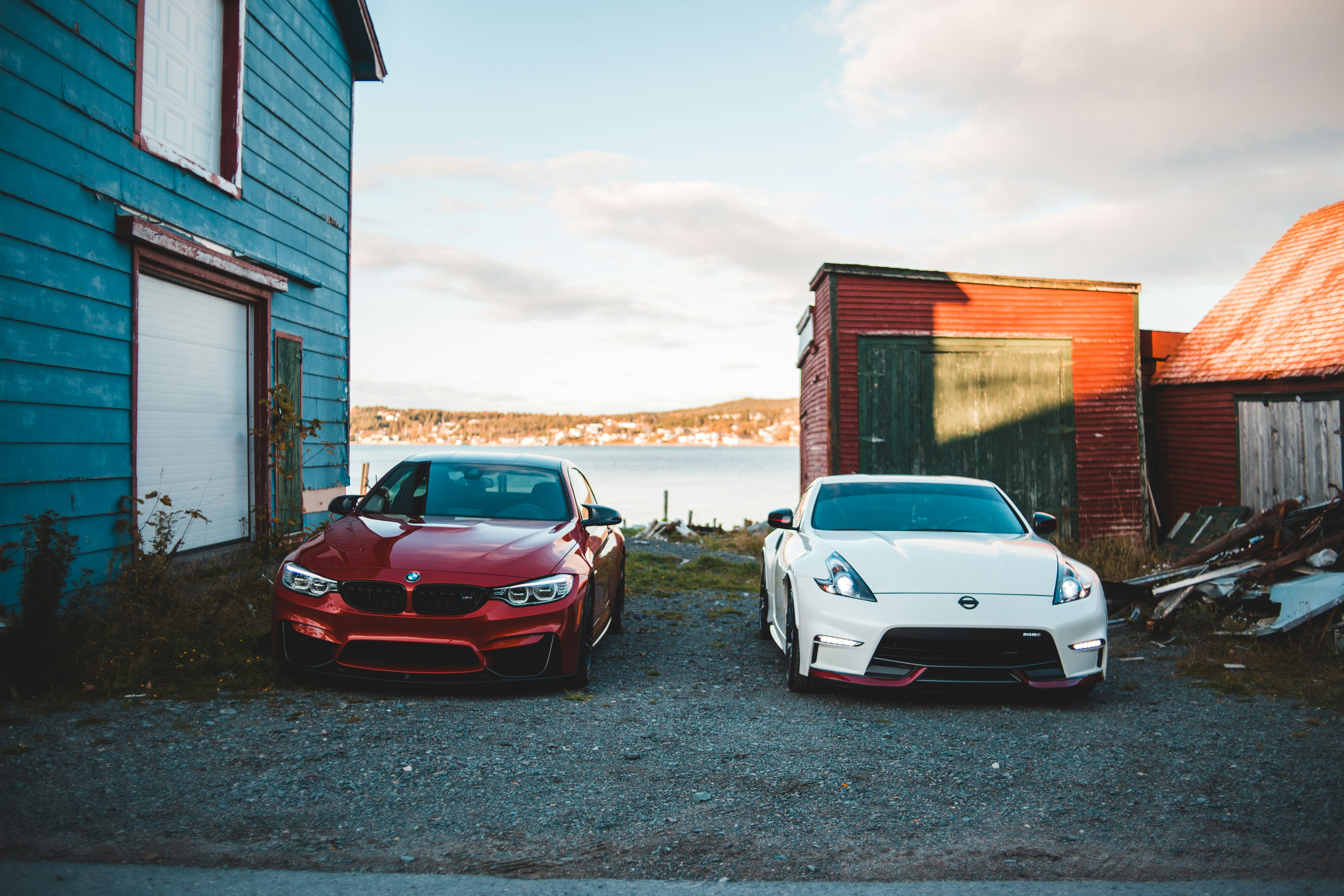 white and red chevrolet camaro parked beside red and white house during daytime