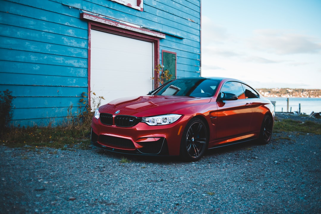 red bmw m 3 coupe parked beside white and brown concrete building